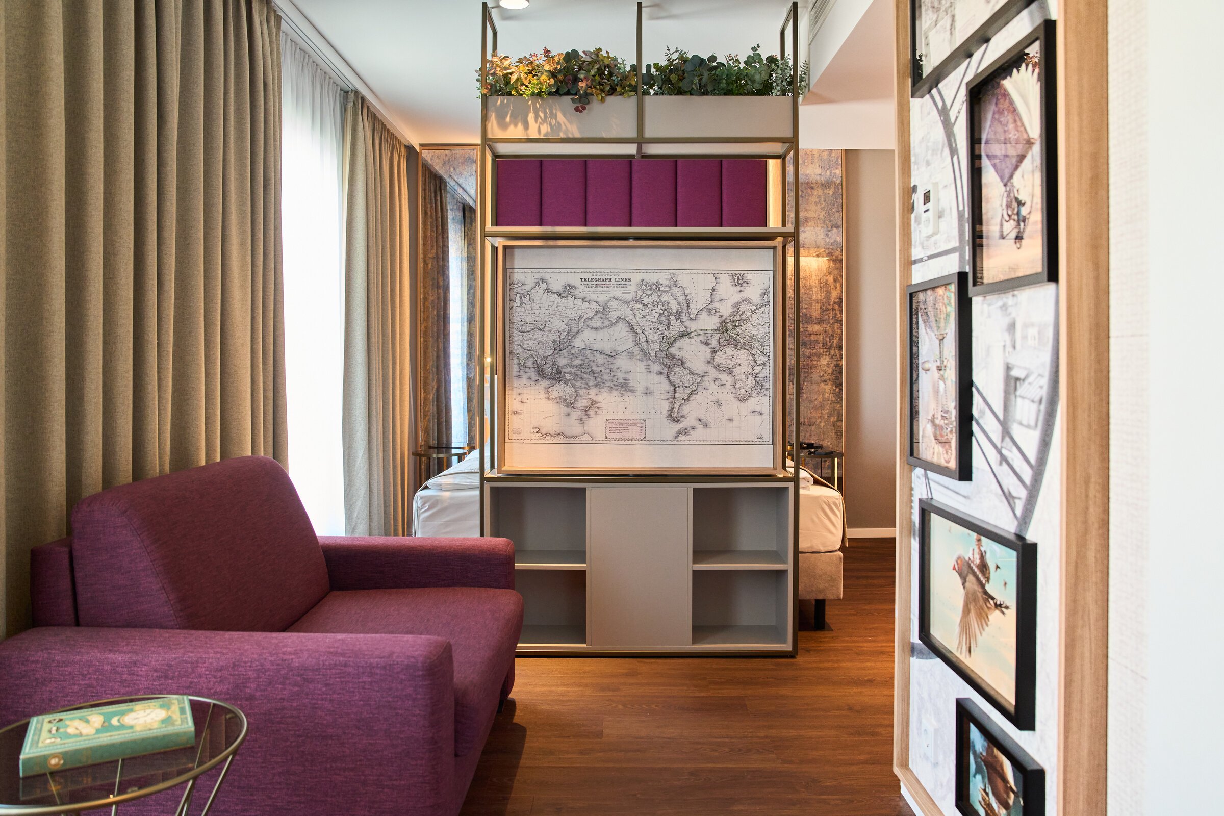 Ein modernes Hotelzimmer im VOYA Hotel am Europa-Park mit einem Raumteiler, der eine Stadtkarte zeigt, und einem lila Sofa.