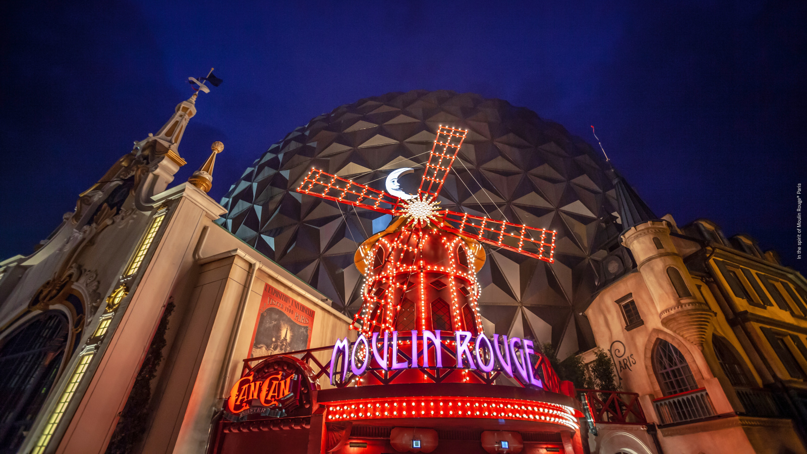Beleuchtetes Windrad des Moulin Rouge mit dem Schriftzug in leuchtenden Farben.